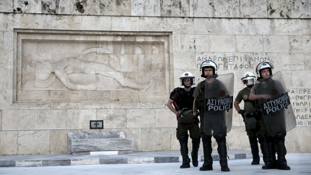Riot policemen stand guard in front of the Tomb of the Unknown Soldier during an anti-bailout demonstration in Athens on Thursday.