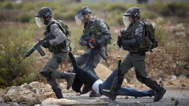 Israeli soldiers drag a wounded Palestinian man away during clashes near the occupied West Bank city of Ramallah.