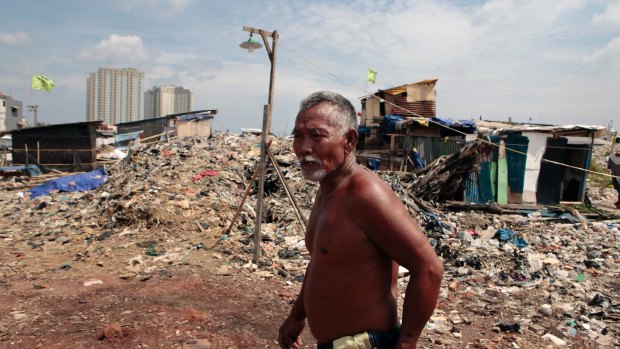 A Kampung Akuarium residents walks through mountains of rubbish and rubble in the makeshift neighbourhood.