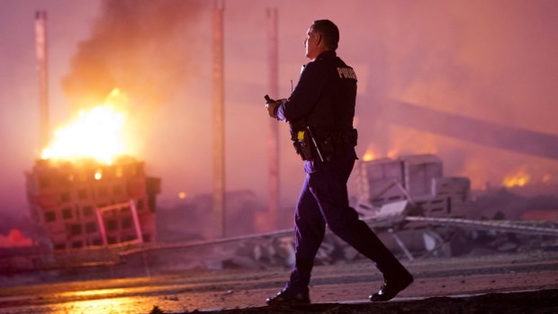 A police officer walks by a blaze on Monday after rioters plunged part of Baltimore into chaos.