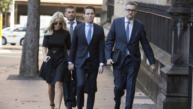 Oliver Curtis (centre) holds his wife Roxy Jacenko's hand as he arrives at the Supreme Court in Sydney on Wednesday to face insider trading charges.