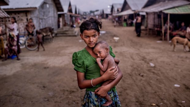 Oma Salema, 12, holds her undernourished brother, one-year-old Ayub Khan, 1, at a camp for Rohingya in Sittwe, Myanmar, this month.