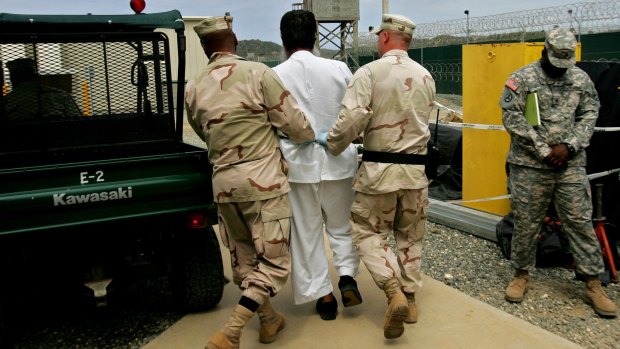 A Guantanamo detainee, centre, escorted by US military personnel at Guantanamo Bay military prison in 2007.