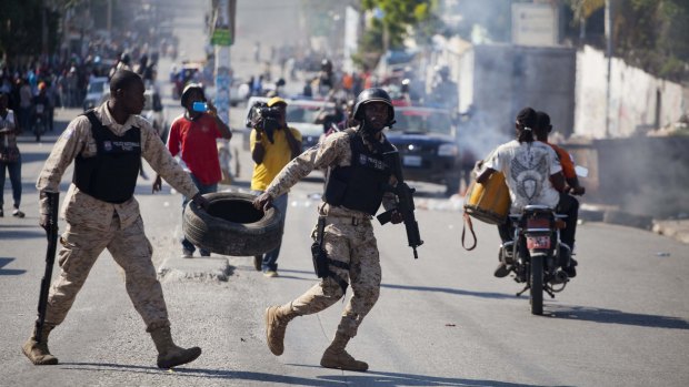 National police officers clear a barricade during a protest against official election results, in Port-au-Prince, Haiti.