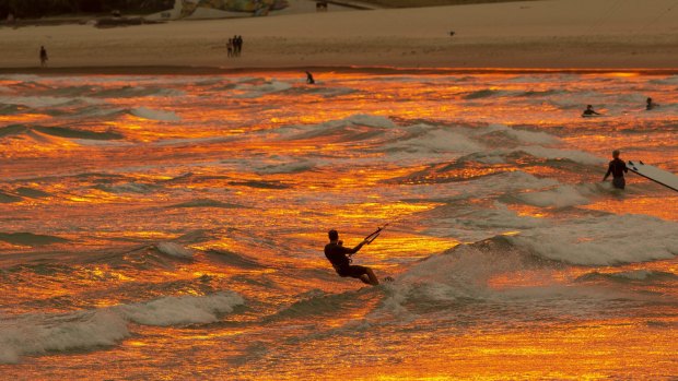 A hazy red sun sets over Bondi Beach.