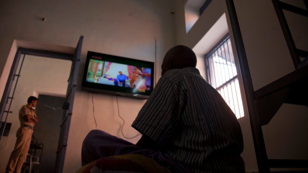 A homeless man who was picked from the streets watches television at Anand Ashram, a shelter home for beggars.