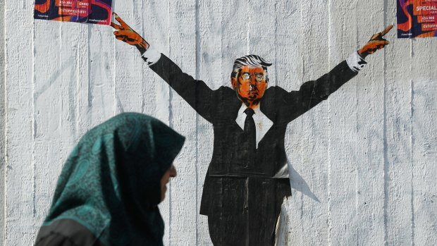 A Muslim woman walks past a street artist's rendition of Donald Trump in Berlin, Germany on Tuesday. 