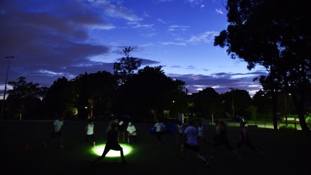Spot the author: An instructor wearing a head torch leads predawn fitness classes by Step Into Life at Lindfield Oval.