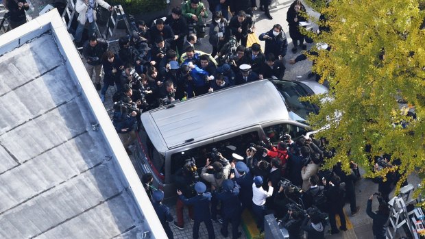 A car carrying Takahiro Shiraishi, 27, leaves Takao Police Station in Hachioji City, Tokyo, surrounded by media.