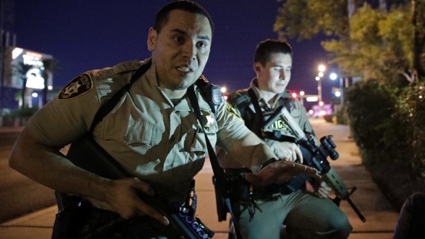 Police officers tell people to take cover near the scene of a shooting near the Mandalay Bay resort and casino on the Las Vegas Strip.