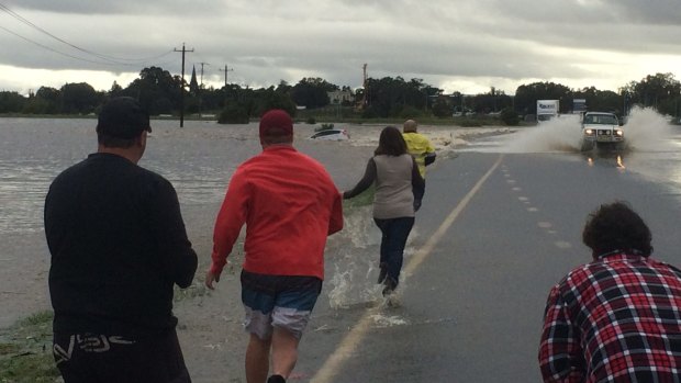 Rescuers rush to Anne Jarmain's car after it was washed in flood waters in Maitland.