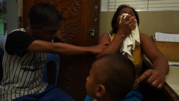 A neighbour comforts pregnant Ruth-Jane Sombrio, widow of Rogie Sebastian, who was killed by police in his home on  September 19. 