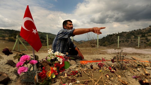 "Why does Erdogan exclude us?": Gungar Kilinc sits at the grave of one of his four relatives killed in May's Soma mine disaster.
