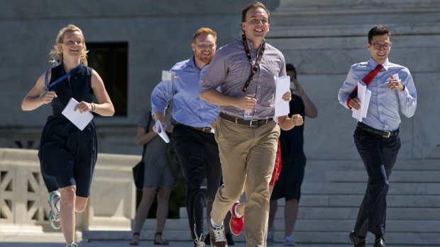 Interns run with a decision across the plaza of the Supreme Court in Washington last month, racing to get to news anchors stationed outside.