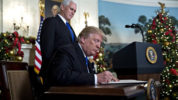 US President Donald Trump signs a proclamation on the status of Jerusalem as Vice-President Mike Pence looks on.