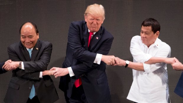 Donald Trump, centre, reacts as he does the "ASEAN-way handshake" with Vietnamese President Tran Dai Quang, left, and Philippines President Rodrigo Duterte last year.