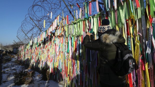 A visitor takes a photo near the North-South Korea border fence decorated with ribbons carrying messages to wish for the reunification of the two Koreas at the Imjingak Pavilion in Paju, South Korea.