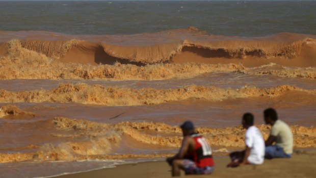 People watch the sea on the coast of Espirito Santo, Brazil, last week after mud from the tailings dam arrived 600 kilometres downstream at the Atlantic Ocean.