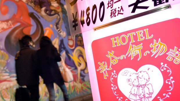 A couple walk past a love hotel in Tokyo's Shibuya district.