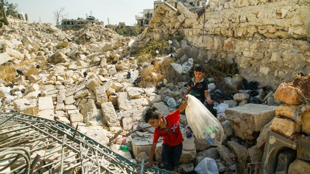 Young boys collect cans in Aleppo where a landmark victory for Assad's forces in the conflict, now in its seventh year, left the area in ruins. 