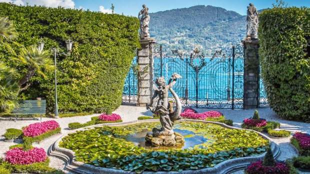 Old fountain with stone statue in beautiful garden, villa Carlotta, Como lake, Italy.