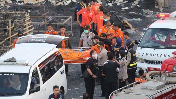 Police officers and rescuers carry a body from the scene of the fire.