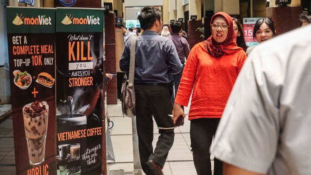Customers walk past a poster advertising iced Vietnamese coffee at the Monviet Cafe in Jakarta.