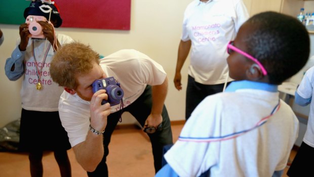 Prince Harry takes a photograph of a young boy using a Fuji Instax camera during a photography activity at the new Mamohato Children's Centre in Maseru, Lesotho.