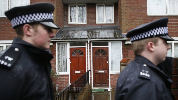 Two police officers walk outside a flat in London  flat that is the former home of Mohammed Emwazi.  