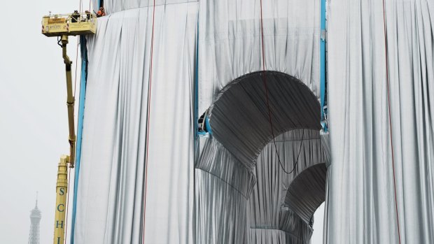 Workers on harnesses spent several days enveloping the 50-metre, 19th century arch in a silvery blue, recyclable plastic curtain, a project first imagined decades ago by the late Bulgarian-born Christo.