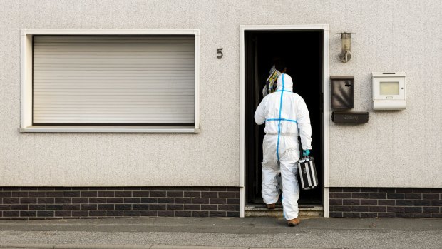 A police investigator in protective cloth enter an apartment in Wallenfels, southern Germany, where the bodies of multiple babies were found.