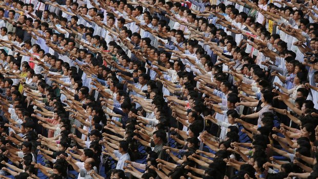 Men and women pump their fists and chant "Defend!" as they carry propaganda slogans calling for reunification of their country during the "Pyongyang Mass Rally on the Day of the Struggle Against the US," attended by approximately 100,000 North Koreans in June.