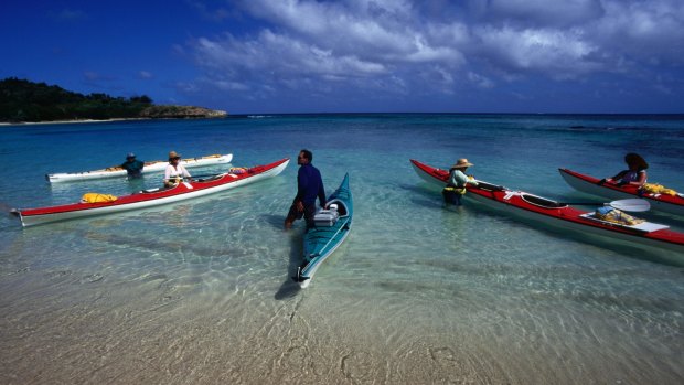 People getting into their sea kayaks near shore.
