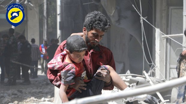 A Syrian man carries an injured boy in Aleppo.
