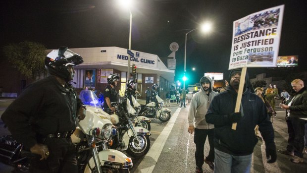 Police officers keep watch as demonstrators block an intersection  during a rally.