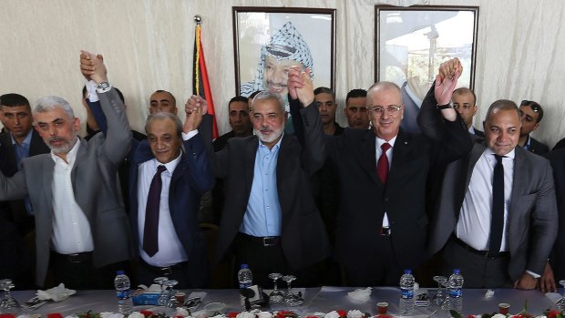 From left to right in front row, Hamas leader in the Gaza Strip Yahya Sinwar, Head of Palestinian General Intelligence Majid Faraj, Head of the Hamas political bureau Ismail Haniya, Palestinian PM Rami Hamdallah and an Egyptian mediator hold their hands up in Gaza City on Monday.