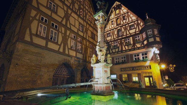 Historic buildings with fountain in the foreground at night in Rothenburg Ob Der Tauber, Germany.