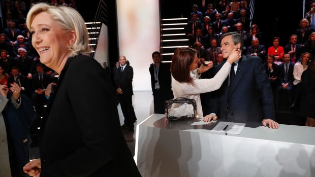 Marine Le Pen, left, smiles as Francois Fillon, right, gets his make-up done.