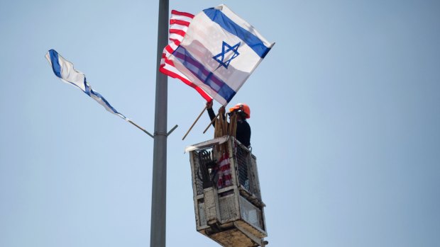 A worker hangs Israeli and US flags on a lamppost along a freeway leading to Jerusalem, days before the planned visit of US President Donald Trump.