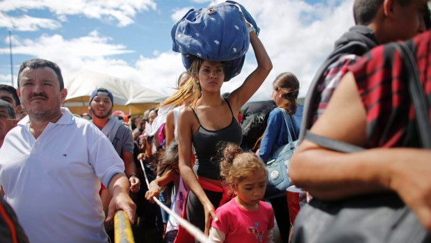 People wait in line to cross the border into Colombia from Venezuela to buy food and medicine in short supply at home. 