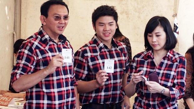 Jakarta Governor Basuki Tjahaja Purnama, left, casts his ballot with his son Nicholas and wife Veronica Tan, all in his campaign's trademark plaid shirt.