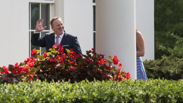 Sean Spicer, outgoing White House press secretary, left, waves while walking to the West Wing of the White House.