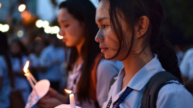 Residents offer flowers, candles, and prayers at the site of a bomb that killed more than a dozen people in Davao city, Philippines. The government blamed Abu Sayyaf for the attack.