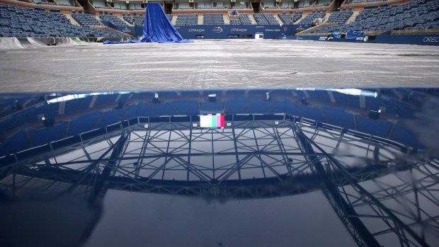 Rainwater puddles up the ledge of a port hole beneath Arthur Ashe Stadium, reflecting the not-yet completed retractable roof, after the women's semi-final matches were postponed.