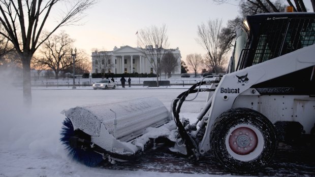 A worker with the National Park Service sweeps snow along Pennsylvania Avenue in front of the White House in Washington, on Thursday.