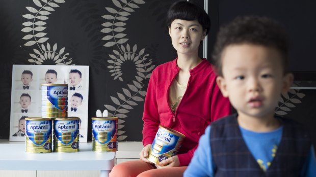 Shanghai mum Cindy Chen, at home with her son and cans of baby formula bought from Australia. Shanghai. Jonathan Browning