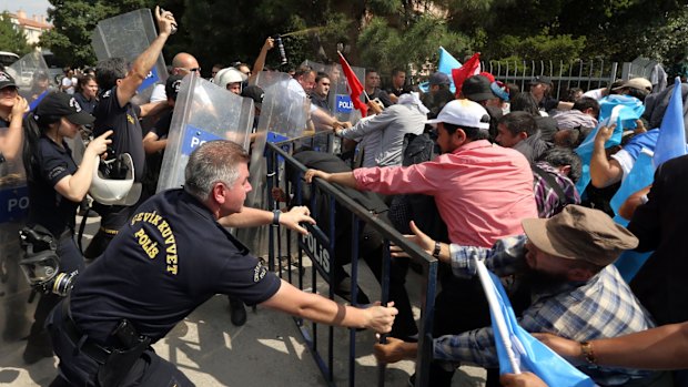 Riot police use pepper spray to push back a group of Uighur protesters trying to break through a barricade outside the Chinese Embassy in Ankara on Thursday.