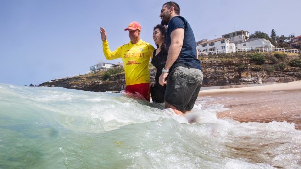 Volunteer lifesaver Paul Borrud teaches new Syrian refugees Alaa (Alan) Alnseer and his sister Lama about water safety at Tamarama.