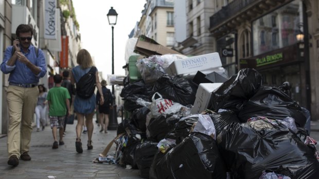 People walk past a pile of rubbish bags in Paris on Wednesday. 