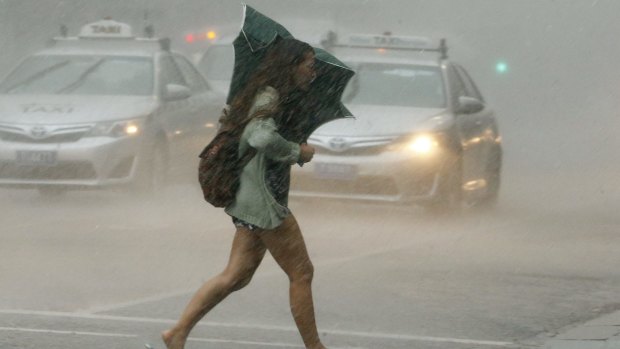 A woman crosses a street during a severe thunderstorm in Sydney.